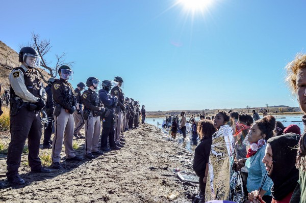 Self-proclaimed water protectors at the Cannonball River in North Dakota face a line of riot law enforcement. CREDIT: Facebook/Rob Wilson