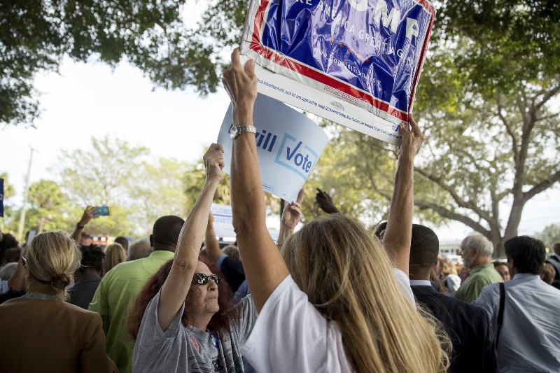 A supporter of Democratic presidential candidate Hillary Clinton attempts to block a Republican presidential candidate Donald Trump supporter from waving a sign as Clinton greets supporters outside an early voting station at the Pompano Beach Amphitheater in Pompano Beach, Fla., Sunday, Oct. 30, 2016. CREDIT: AP Photo/Andrew Harnik
