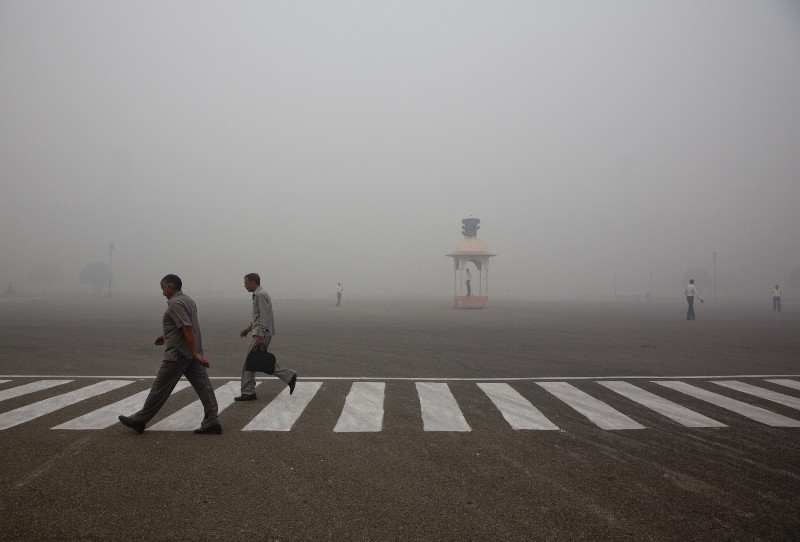 Indians walk to work as Delhi traffic police officers manage an intersection enveloped by smoke and smog, on the morning following Diwali festival in New Delhi. CREDIT: AP/Manish Swarup