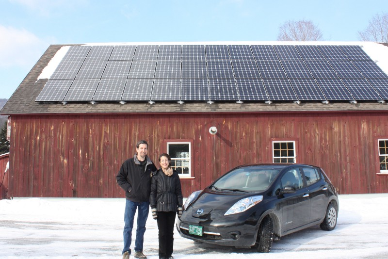 Bill Laberge and wife Lisa with their solar panels and electric car. CREDIT: Grassroots Solar