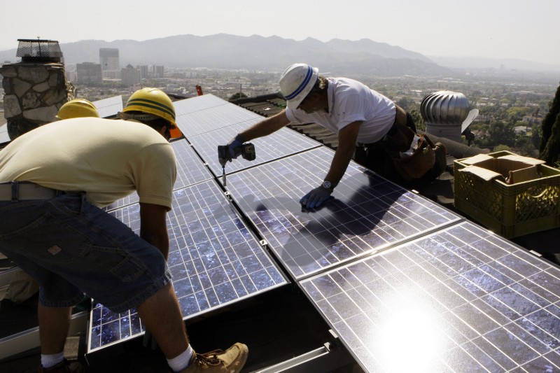 Installers from California Green Design put solar electrical panels on the roof of a home in Glendale, Calif. CREDIT: AP Photo/Reed Saxon