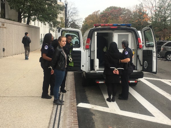 Two of the seventeen people arrested are loaded into a police van outside the Senate offices. CREDIT: Kira Lerner