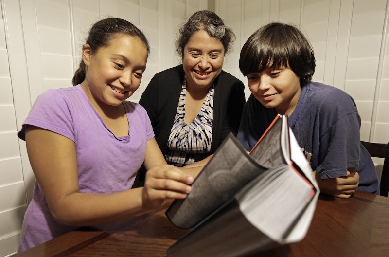 In this Nov. 10, 2014 photo, Rosaisela Rodriguez, center, reads with her children Isabel Gutierrez, left, and Rafael Gutierrez, at their home in Pleasant Hill, California. CREDIT: AP/Ben Margot