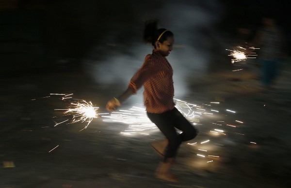 An Indian girl lights firecrackers as part of Diwali festivities. CREDIT: AP/Rajanish Kakade