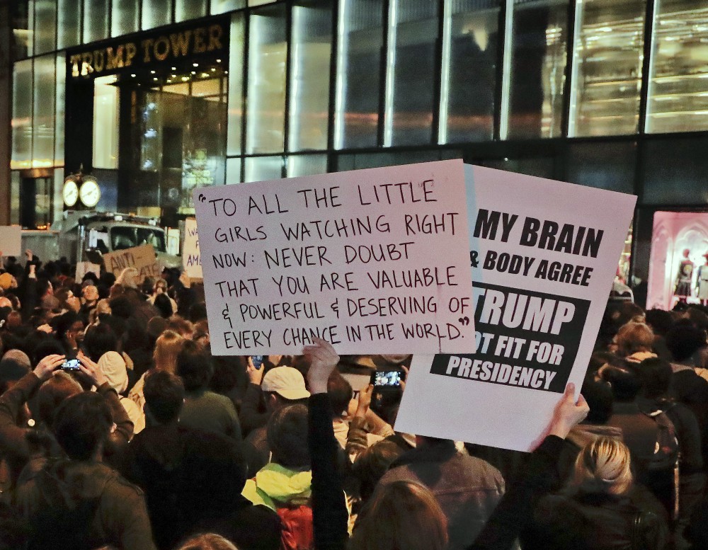 Protesters gather on Fifth Avenue outside Trump Tower, Wednesday, Nov. 9, 2016, in New York, in opposition of Donald Trump’s presidential election victory. The sign on the left is a quote from Democratic candidate Hillary Clinton’s concession speech. CREDIT: AP Photo/Julie Jacobson