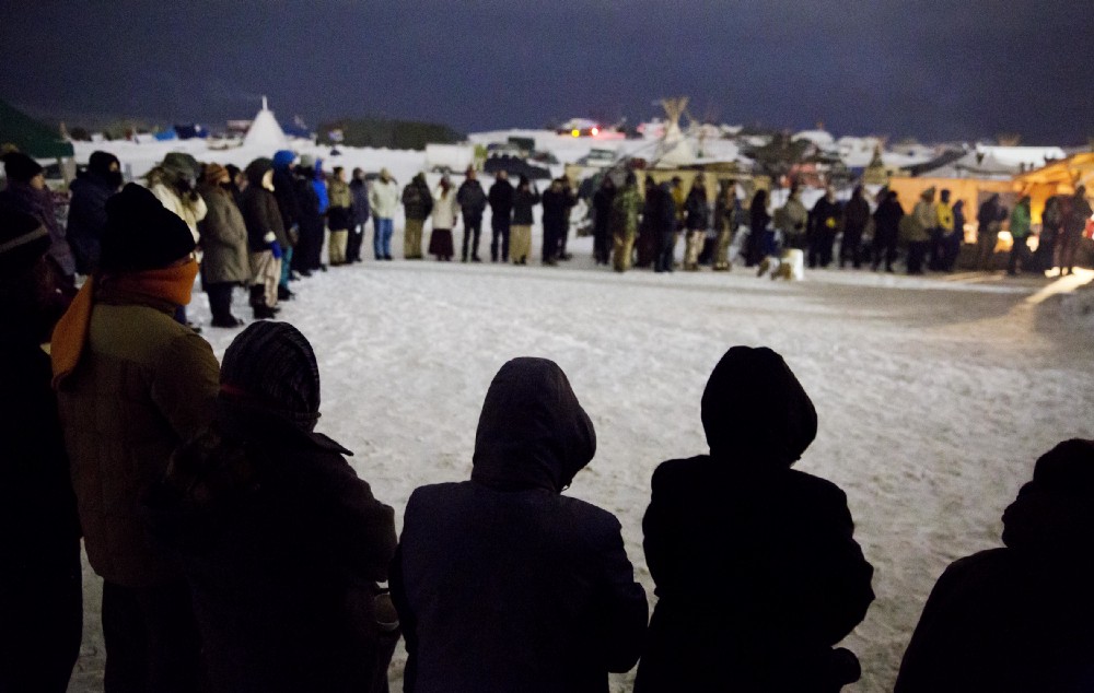 People form a circle for the morning prayer at the Oceti Sakowin camp. CREDIT: AP Photo/David Goldman