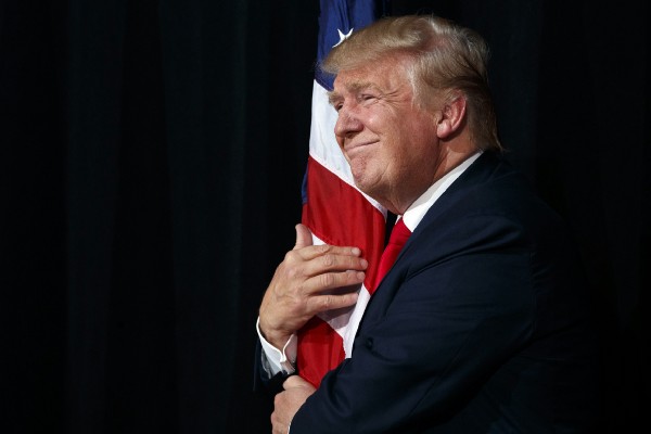 Donald Trump hugs an American flag as he arrives to speak to a campaign rally, Monday, Oct. 24, 2016, in Tampa, Fla. CREDIT: AP Photo/ Evan Vucci