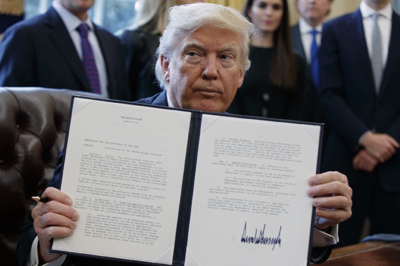 President Donald Trump shows off his signature on an executive order about the Dakota Access pipeline, Tuesday, Jan. 24, 2017, in the Oval Office of the White House in Washington. CREDIT: AP Photo/Evan Vucci