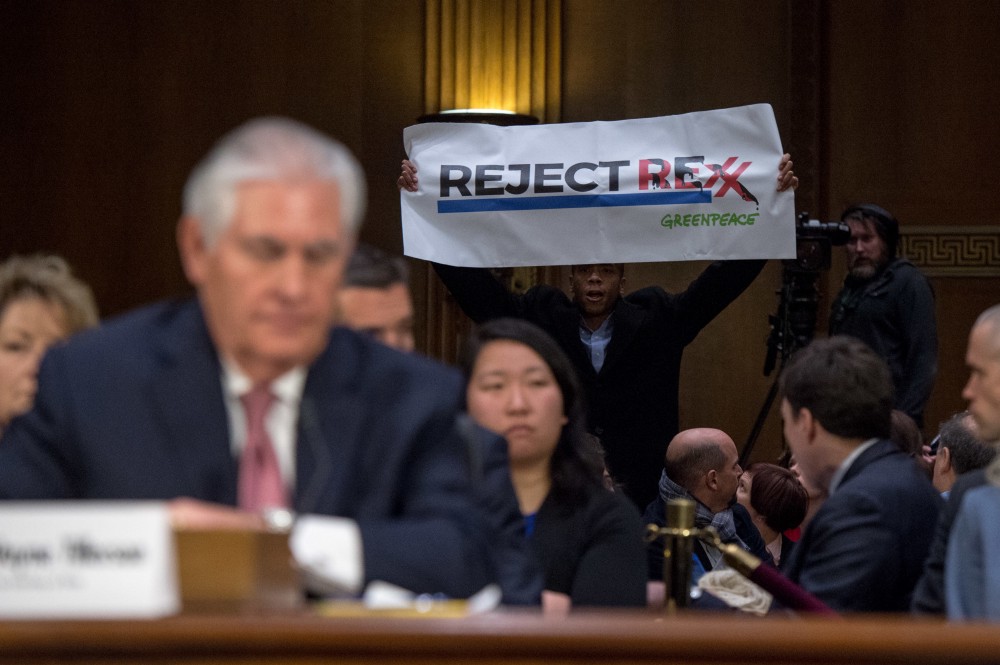 Greenpeace activist James Burch of San Francisco, California, holds up a protest sign reading “Reject Rexx”. CREDIT: Ken Cedeno/Greenpeace