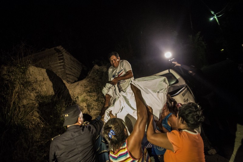 Relatives of a Mara Salvatrucha gang member lift his body in a body bag into the back of a forensic vehicle, after retrieving his remains from a steep gully after he was shot dead in a confrontation with police, in Olocuilta, El Salvador, Wednesday, May 27, 2015. CREDIT: AP Photo/Manu Brabo