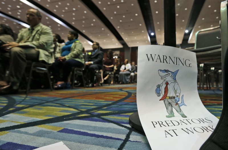 A sign warning of predatory payday lenders leans up against a chair during a speech by Consumer Financial Protection Bureau Director Richard Cordray, in Richmond, Va., Thursday, March 26, 2015. CREDIT: AP Photo/Steve Helber