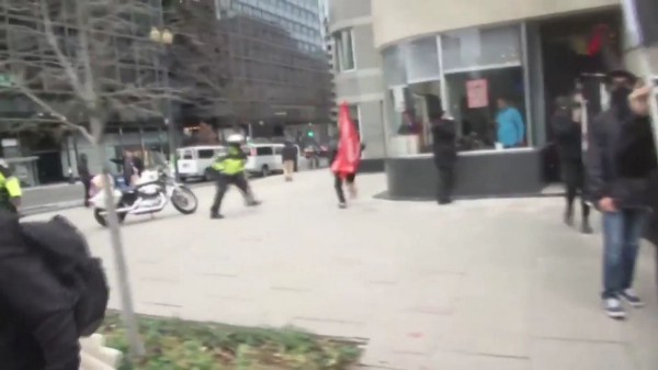 A demonstrator carrying a large red flag was able to run past police and apparently escape the initial push to “kettle” everyone in the area. CREDIT: YouTube/Screengrab