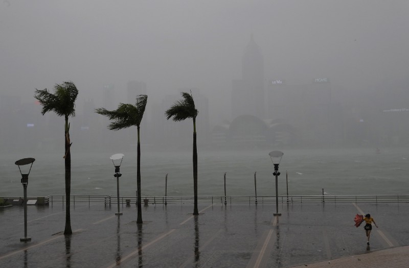 A woman braves the wind on the waterfront of Victoria Habour as Typhoon Haima approaches Hong Kong, Friday, Oct. 21, 2016. CREDIT: AP Photo/Vincent Yu