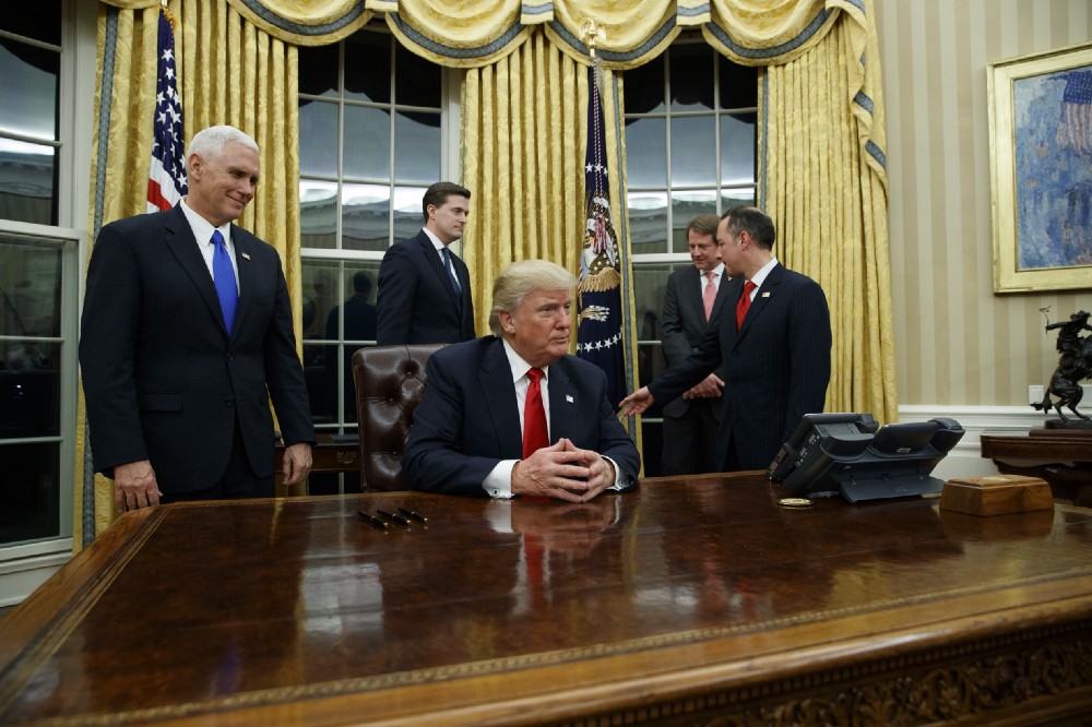 Vice President Mike Pence, left, watches as President Donald Trump prepares to sign his first executive order, Friday, Jan. 20, 2017, in the Oval Office of the White House in Washington. CREDIT: AP Photo/Evan Vucci