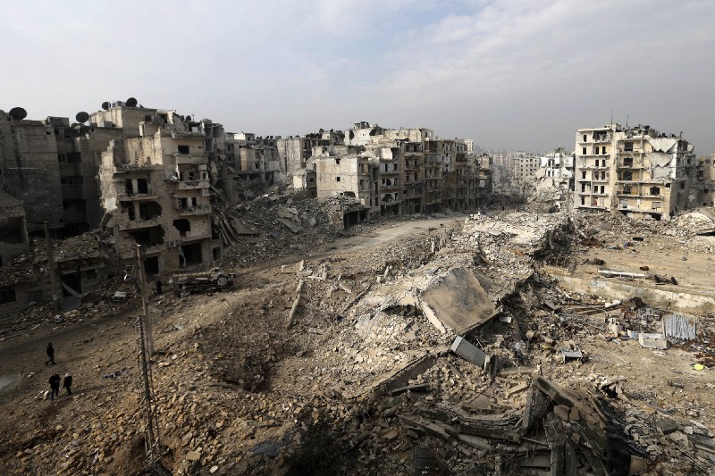 People walk through mounds of rubble on Friday, Jan 20, 2017 which used to be high rise apartment buildings in the once rebel-held Ansari neighborhood in the eastern Aleppo, Syria. CREDIT: AP Photo/Hassan Ammar