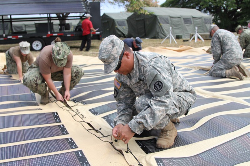 The U.S. Army is increasingly deploying solar power in the field. Above, soldiers assemble a solar shade canopy during a training exercise. CREDIT: United States Army