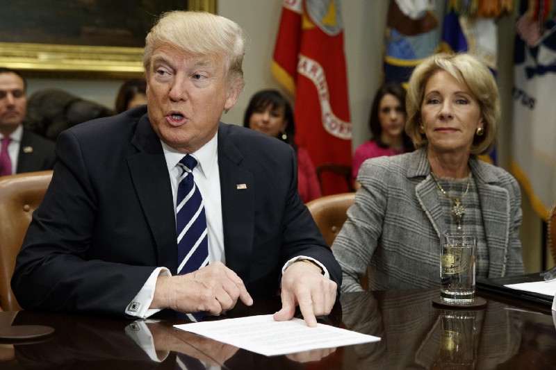 President Donald Trump accompanied by Education Secretary Betsy DeVos, speaks during a meeting with parents and teachers, Tuesday, Feb. 14, 2017, in the Roosevelt Room of the White House in Washington. CREDIT: AP/Evan Vucci