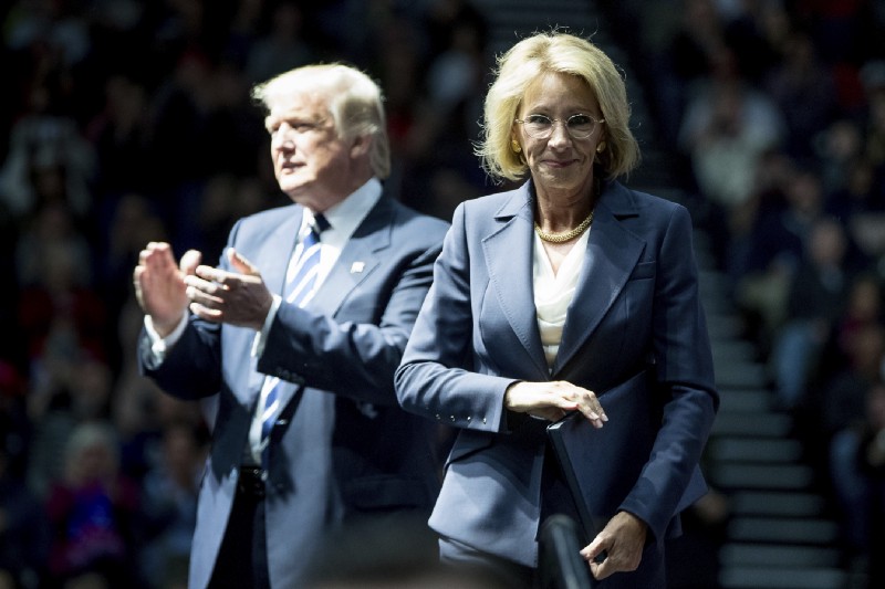 President-elect Donald Trump, left, applauds after his pick for Education Secretary Betsy DeVos, right, finishes speaking at a rally at DeltaPlex Arena, Friday, Dec. 9, 2016, in Grand Rapids, Mich. CREDIT: AP Photo/Andrew Harnik