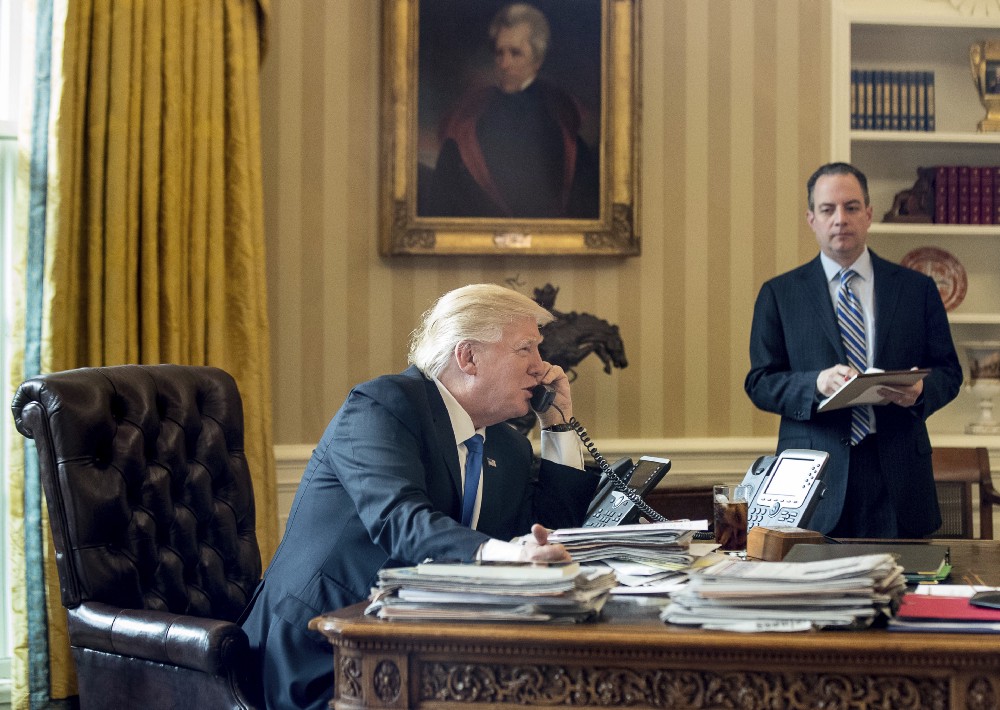 President Donald Trump, accompanied by Chief of Staff Reince Priebus speaks on the phone with Russian President Vladimir Putin, Saturday, Jan. 28, 2017, in the Oval Office at the White House in Washington. CREDIT: AP Photo/Andrew Harnik