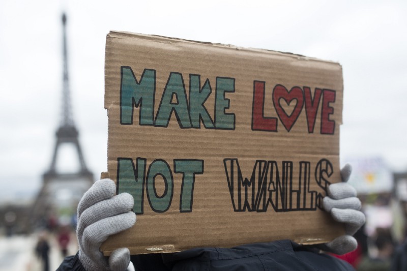 A woman holds a banner reading “ Make love not walls” during a gathering in Paris to protest U.S. President Donald Trump’s recent travel ban to the U.S. CREDIT: AP Photo/Kamil Zihnioglu