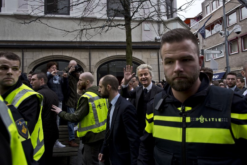 Firebrand anti-Islam lawmaker Geert Wilders, second right, surrounded by police officers and security guards as he waves to supporters during a campaign stop in Heerlen, Netherlands, Saturday, March 11, 2017. CREDIT: AP Photo/Muhammed Muheisen