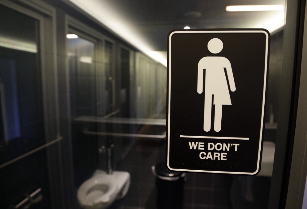 FILE — This Thursday, May 12, 2016, file photo, shows a sign outside a restroom at 21c Museum Hotel in Durham, N.C. The Associated Press has determined that North Carolina’s law limiting LGBT protections will cost the state more than $3 billion in lost business over a dozen years.That’s despite Republican assurances that the “bathroom bill” isn’t hurting the economy. CREDIT: AP Photo/Gerry Broome, File