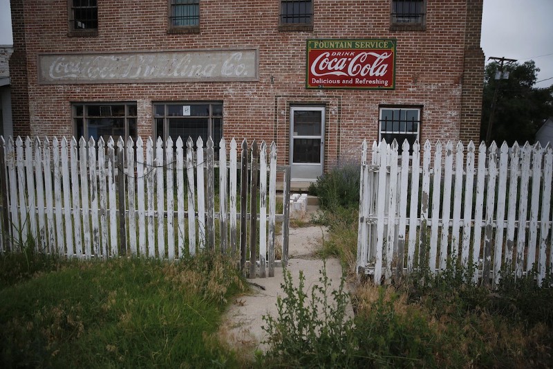 Weeds grow around an old building and picket fence in Rocky Ford, Colo., on July 1, 2016. Otero County is a rural and increasingly impoverished part of southern Colorado. CREDIT: Brennan Linsley