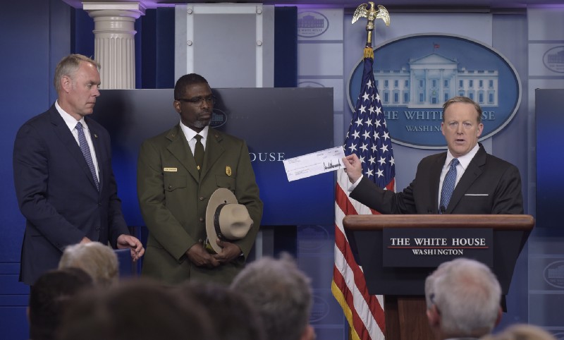 White House press secretary Sean Spicer, right, holds up a check during the daily briefing with Interior Secretary Ryan Zinke, left, and Harpers Ferry National Historic Park Superintendent Tyrone Brandyburg. CREDIT: AP Photo/Susan Walsh