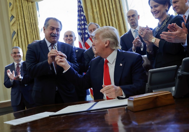 President Donald Trump gives the pen he used to sign an executive order to Dow Chemical President, Chairman and CEO Andrew Liveris. CREDIT: AP Photo/Pablo Martinez Monsivais, File