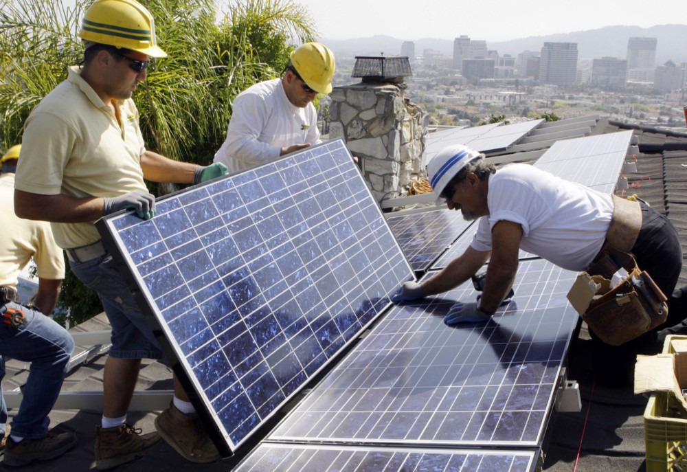 Workers install solar panels in Glendale, California. CREDIT: AP/Reed Saxon