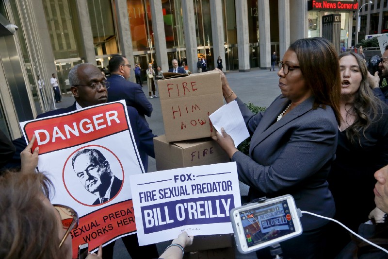 A security guard blocks an entry way as New York Public Advocate Letitia James, second from right, and protestors attempt to deliver boxes of petitions during a rally outside Fox News headquarters, calling for the network to fire Bill O’Reilly, Tuesday April 18, 2017, in New York. CREDIT: AP Photo/Bebeto Matthews