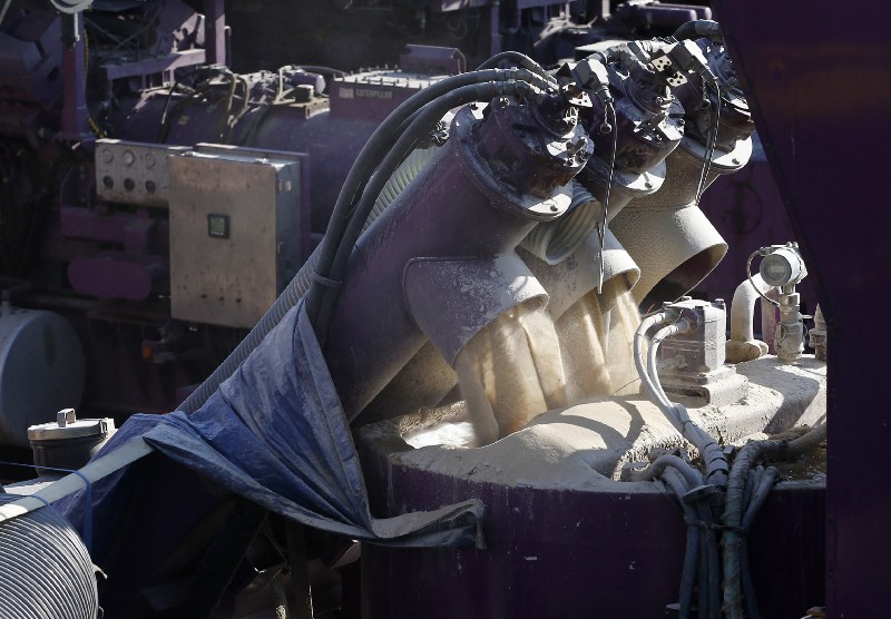 A machine mixes sand and water, left, before it is pumped underground during a hydraulic fracturing operation at an Encana Corp. well pad near Mead, Colo. CREDIT: AP Photo/Brennan Linsley