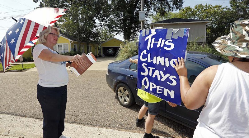 Abortion opponent Mary McLaurin, left, challenges clinic defenders who have blocked her sidewalk access from a car transporting a patient to the Jackson Women’s Health Organization Clinic in Jackson, Miss.