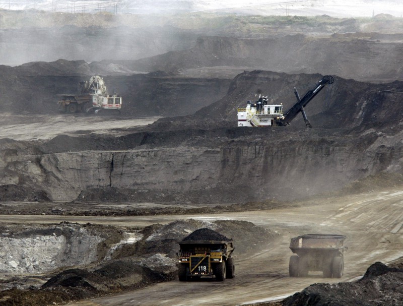 Mining trucks carry loads of oil laden sand after being loaded by huge shovels at the Albian Sands oils sands project in Ft. McMurray, Alberta, Canada. CREDIT: AP Photo/Jeff McIntosh