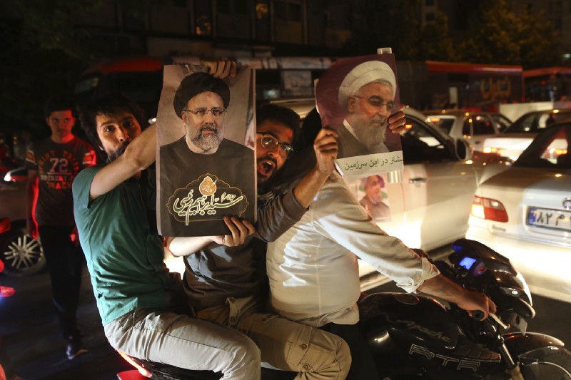 A supporter of Iranian President Hassan Rouhani, right, holds his poster as the other one holds a poster of his main rival Ebrahim Raisi during a street campaign ahead May 19 presidential election in downtown Tehran, Iran, Wednesday, May 17, 2017. CREDIT: AP Photo/Vahid Salemi