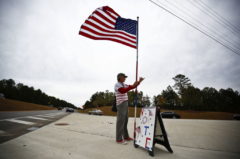 Roy Brook, 67, of Bessemer, Ala., stands near a busy highway intersection and encourages people to get out and vote, Tuesday, Nov. 8, 2016, in Hoover, Ala. CREDIT: AP Photo/Brynn Anderson