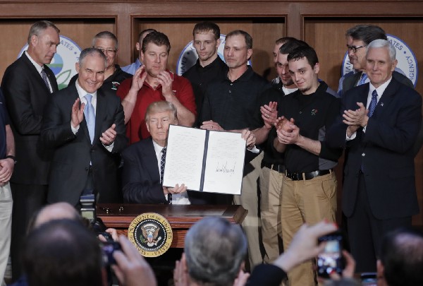 President Donald Trump, accompanied by coal miners, holds up a signed executive order at EPA headquarters calling for review of the Clean Power Plan. CREDIT: AP Photo/Pablo Martinez Monsivais