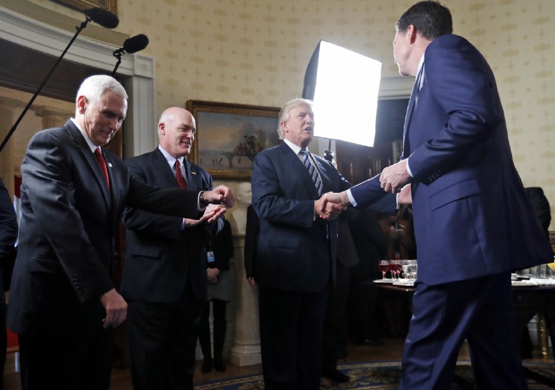 Vice President Mike Pence, left, and Secret Service Director Joseph Clancy stand as President Donald Trump shakes hands with FBI Director James Comey during a reception for inaugural law enforcement officers and first responders in the Blue Room of the White House, Sunday, Jan. 22, 2017 in Washington. CREDIT: AP Photo/Alex Brandon