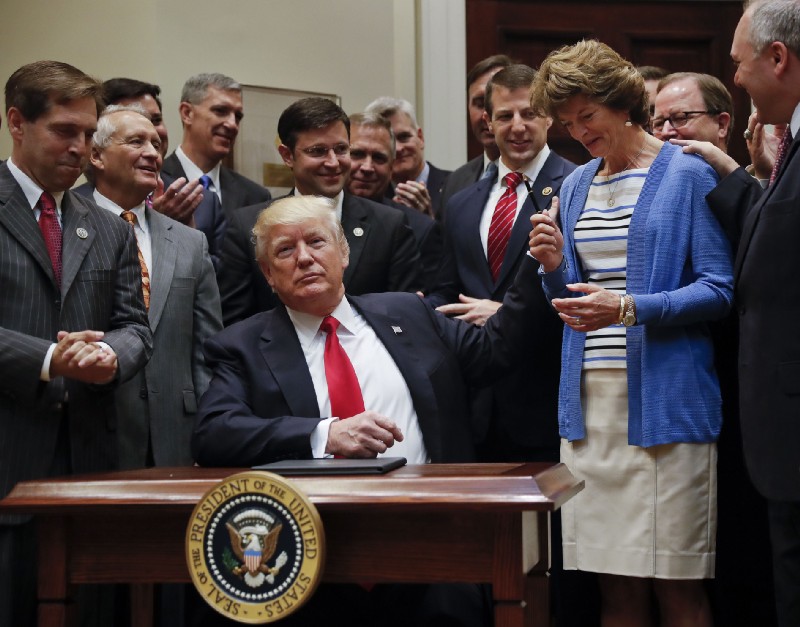 In an April 28, 2017 photo, President Donald Trump gives the pen he used to sign an executive order to Sen. Lisa Murkowski (R-AK), who heads the committee that conducts hearings on Federal Energy Regulatory Commission nominees. CREDIT: AP Photo/Pablo Martinez Monsivais.
