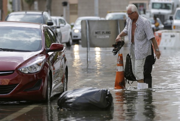 A hotel guest is escorted through a flooded street in Miami Beach on September 30, 2015. CREDIT: AP Photo/Lynne Sladky