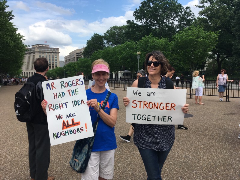 Cheryl Moore (left) holds a sign reading, “Mr. Rogers had the right idea. We are all neighbors” at the May Day rally in Washington, D.C. CREDIT: Esther Yu Hsi Lee