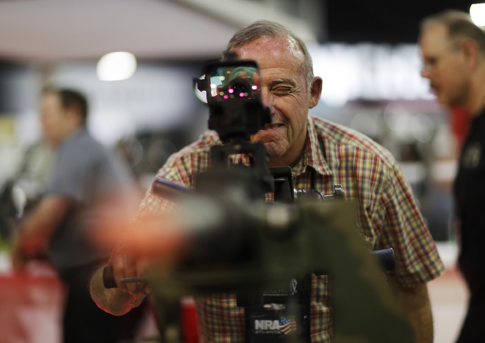 Dick Burch, of Warner Robins, Ga., looks through a .50-caliber machine gun on display at the Nation Riffle Association’s annual convention in Atlanta, Friday, April 28, 2017. CREDIT: AP Photo/David Goldman