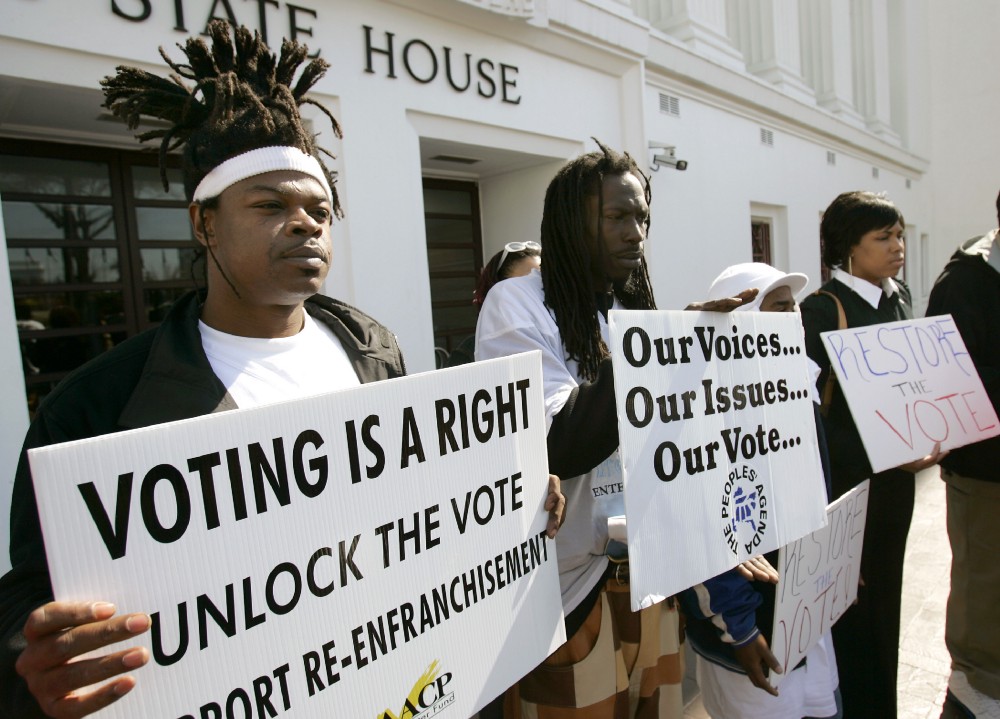Supporters for a bill that would automatically restore voting rights to convicted felons upon their release from prison hold up signs supporting the bill during a news conference Thursday, Feb. 9, 2006, in front of the State House in Montgomery, Ala. CREDIT: AP Photo/Rob Carr
