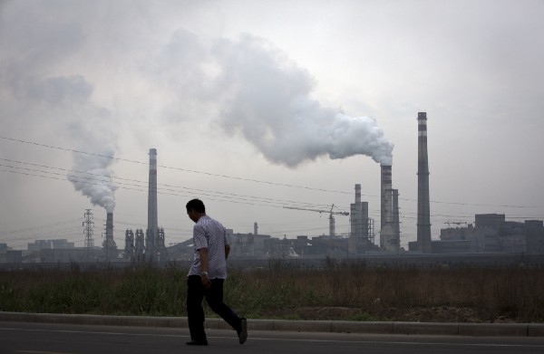 A man walks past a coal-powered steel plant in Tianjin, China. CREDIT: AP Photo/Andy Wong