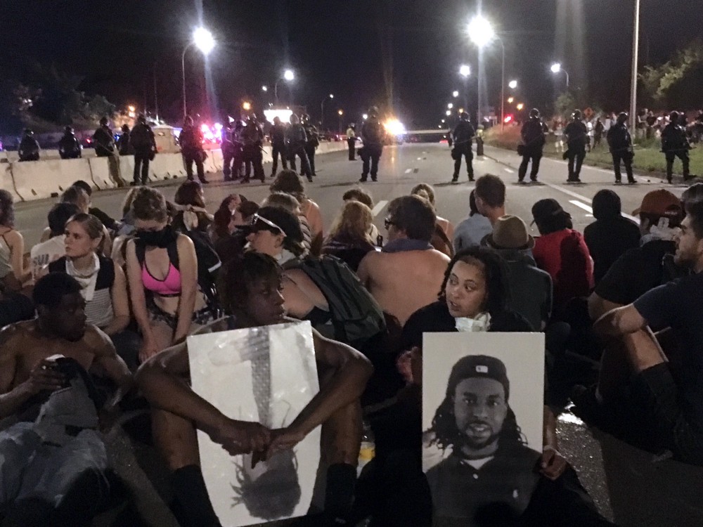 Protesters blocking a highway in Minnesota hold pictures of slain Philando Castile. CREDIT: AP Photo/Joe Danborn