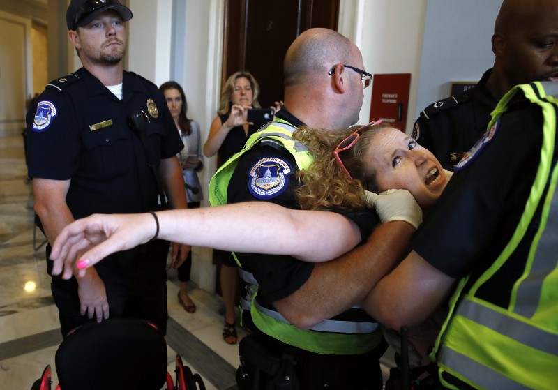 Stephanie Woodward, of Rochester, NY, who has spina bifida and uses a wheelchair, is removed from a sit-in at Senate Majority Leader Mitch McConnell’s office as she and other disability rights advocates protest proposed funding caps to Medicaid, Thursday, June 22, 2017, on Capitol Hill in Washington. CREDIT: AP Photo/Jacquelyn Martin