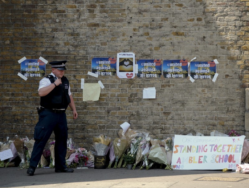 A policeman stands near floral tributes left after an incident, close to Finsbury Park Tube Station, in north London, Monday, June 19, 2017. CREDIT: AP Photo/Alastair Grant