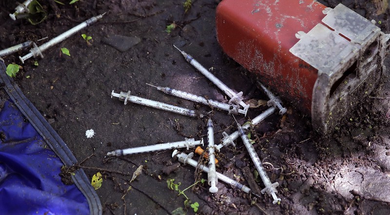 This June 2017 photo shows discarded used hypodermic needles at an encampment where opioid addicts shoot up along the Merrimack River in Lowell, MA. CREDIT: AP Photo/Charles Krupa