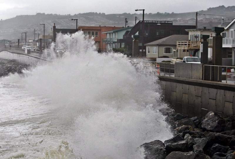 Waves pound a wall near buildings in Pacifica, CA. CREDIT: AP Photo/Paul Sakuma, File