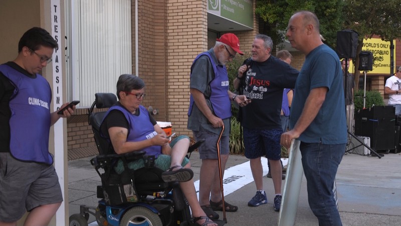 Clinic escorts wait along the property line for patients to arrive as protesters try to engage them in conversation. CREDIT: Katelyn Marmon